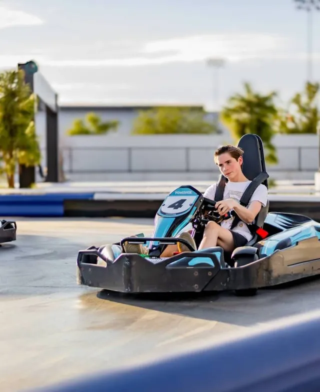 Person driving a black go-kart on an outdoor track in daylight