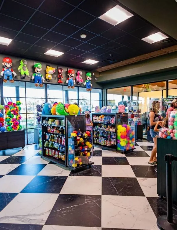 Colorful toy and claw machine store with checkered floor and plush prizes near front windows